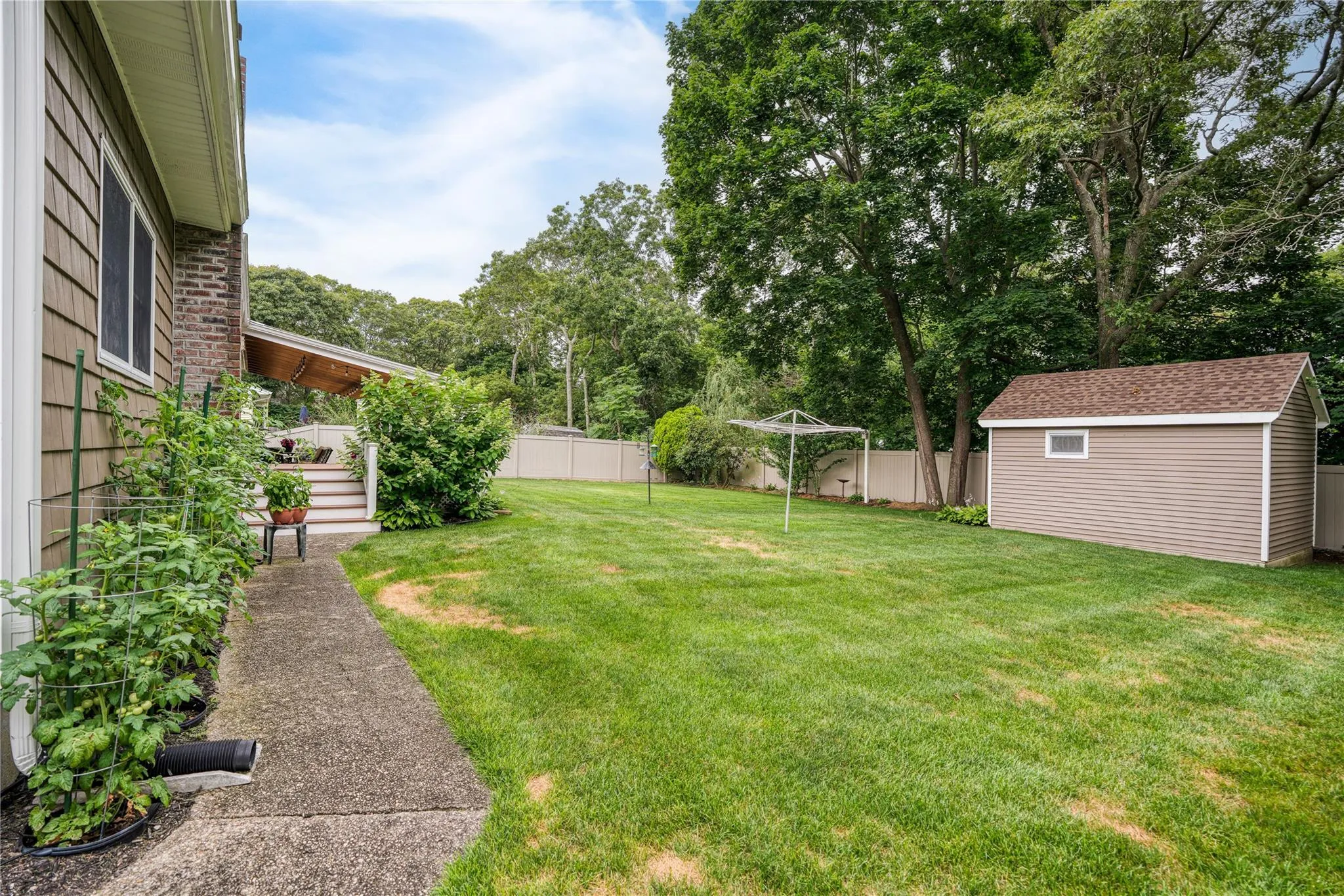 Fenced backyard with a storage shed and view of scattered trees