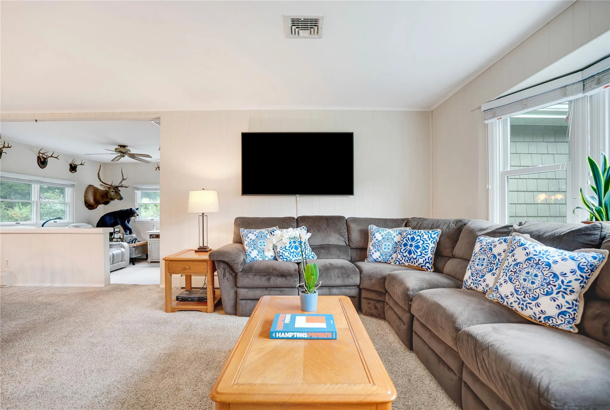 Carpeted living area with ceiling fan and ornamental molding