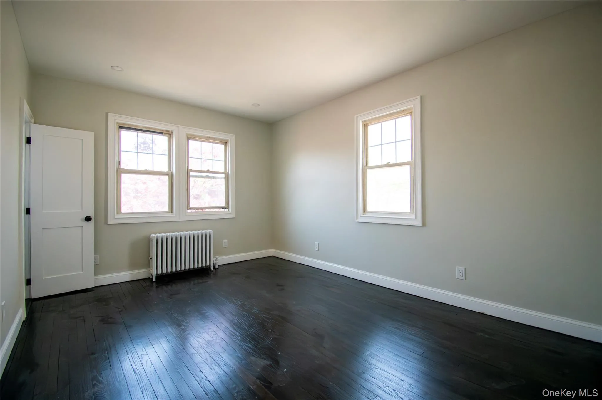 Spare room with radiator heating unit and dark wood finished floors Spare room with radiator heating unit and dark wood finished floors