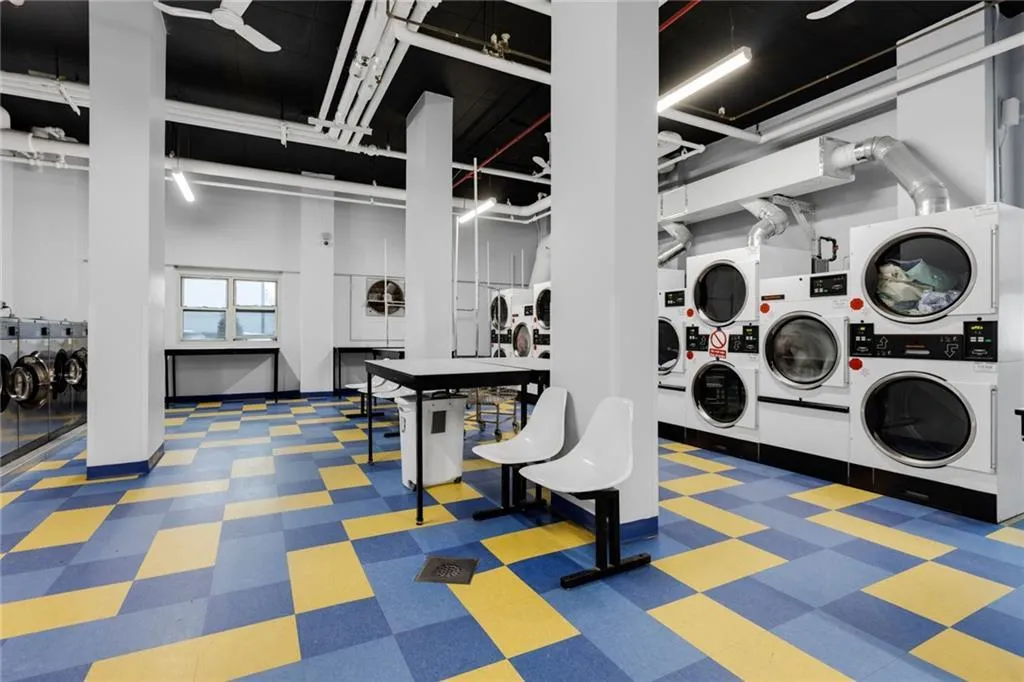Community laundry room with estacked washer and dryer, tile patterned floors, and washer and clothes dryer Community laundry room with estacked washer and dryer, tile patterned floors, and washer and clothes dryer