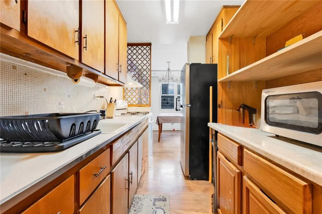 Kitchen with tasteful backsplash, appliances with stainless steel finishes, light wood-type flooring, and light countertops Kitchen with tasteful backsplash, appliances with stainless steel finishes, light wood-type flooring, and light countertops