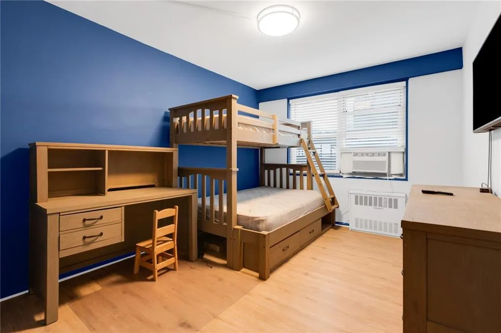 Bedroom with radiator heating unit and light wood-style floors Bedroom with radiator heating unit and light wood-style floors