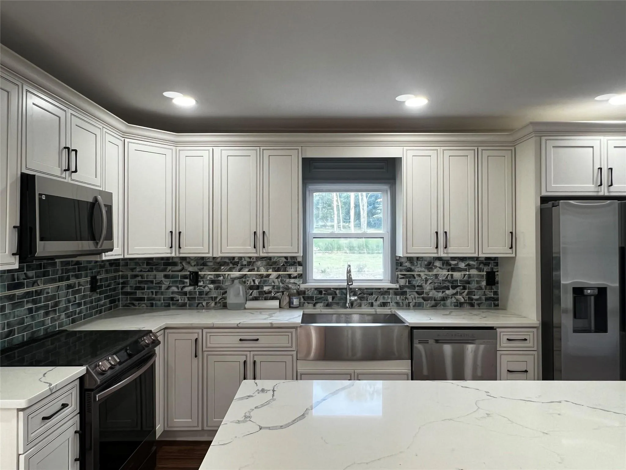 Kitchen featuring stainless steel appliances, decorative backsplash, light stone countertops, recessed lighting, and dark wood-type flooring Kitchen featuring stainless steel appliances, decorative backsplash, light stone countertops, recessed lighting, and dark wood-type flooring