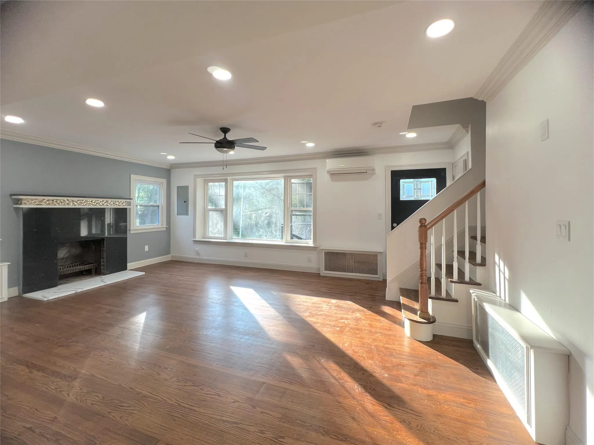 Unfurnished living room featuring ornamental molding, recessed lighting, ceiling fan, wood finished floors, and stairs Unfurnished living room featuring ornamental molding, recessed lighting, ceiling fan, wood finished floors, and stairs