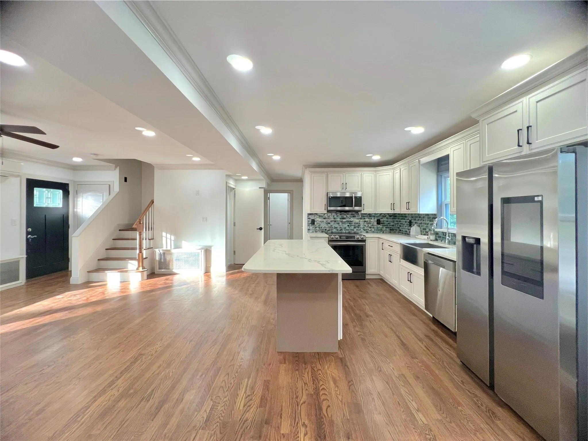 Kitchen with appliances with stainless steel finishes, decorative backsplash, crown molding, a kitchen island, and white cabinets Kitchen with appliances with stainless steel finishes, decorative backsplash, crown molding, a kitchen island, and white cabinets