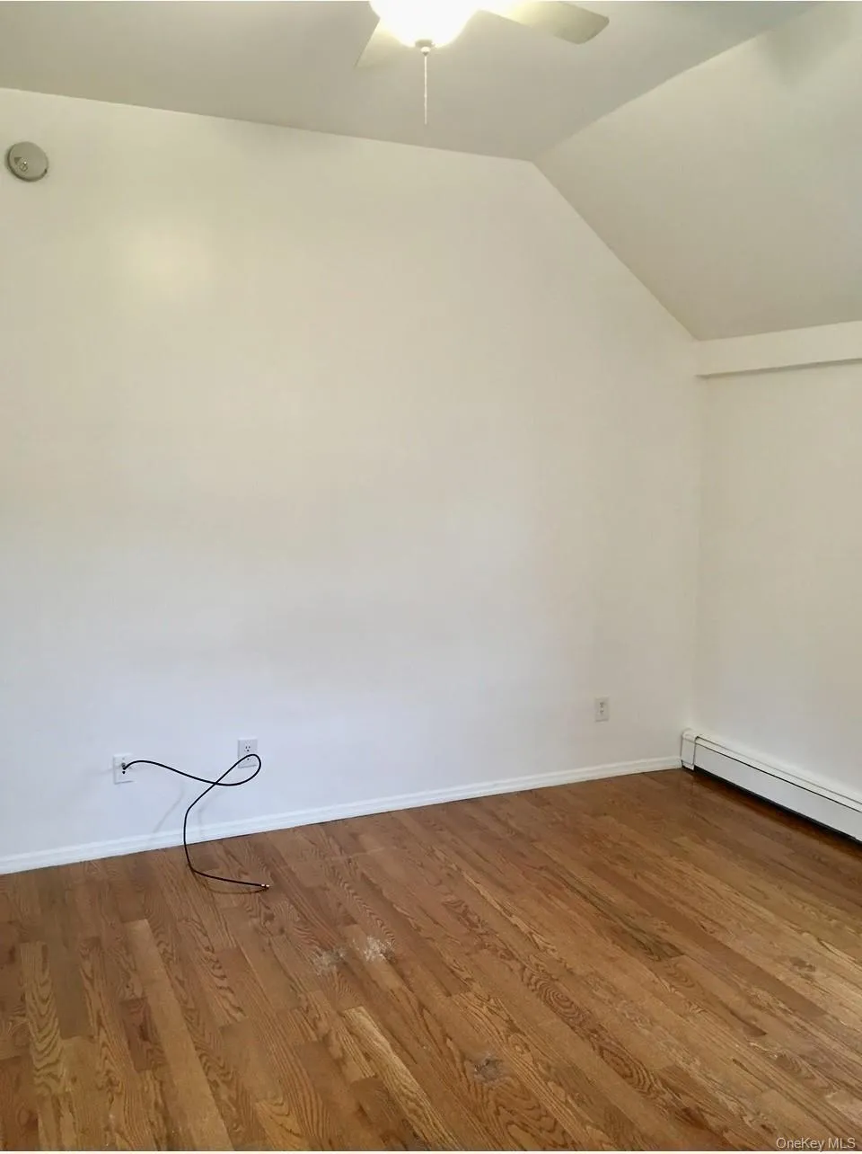 Additional living space with a baseboard radiator, ceiling fan, wood finished floors, and vaulted ceiling Additional living space with a baseboard radiator, ceiling fan, wood finished floors, and vaulted ceiling