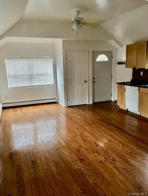 Foyer featuring vaulted ceiling, dark wood-type flooring, ceiling fan, and a baseboard heating unit Foyer featuring vaulted ceiling, dark wood-type flooring, ceiling fan, and a baseboard heating unit