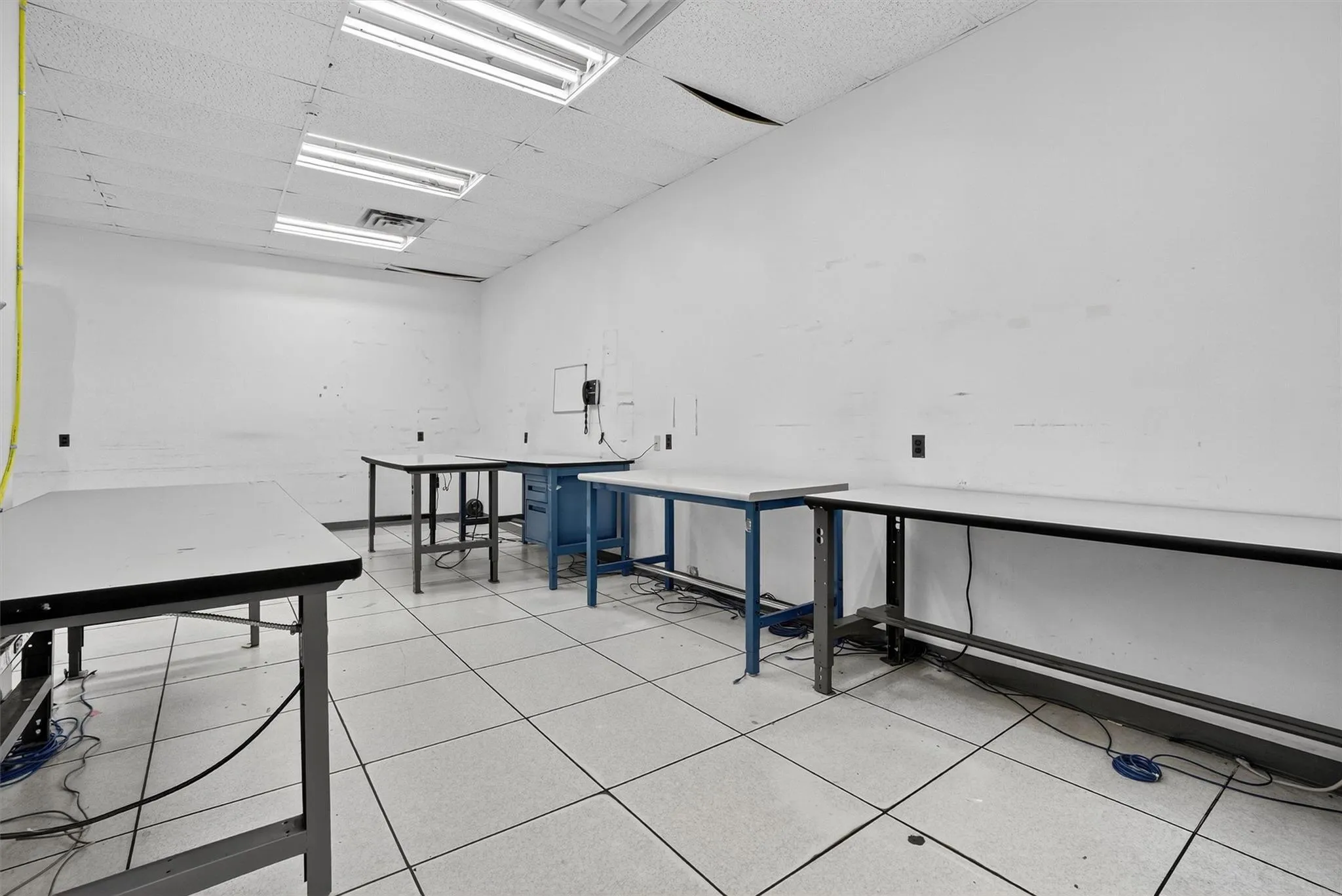 Miscellaneous room featuring a workshop area, a drop ceiling, and light tile patterned flooring Miscellaneous room featuring a workshop area, a drop ceiling, and light tile patterned flooring