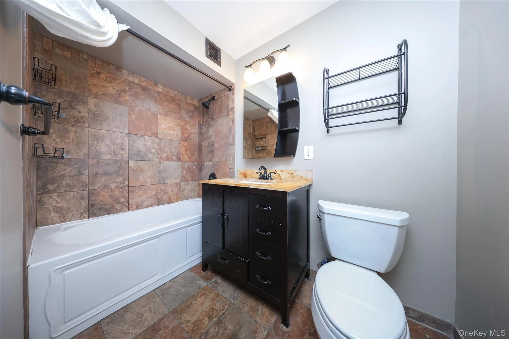 Bathroom with stone tile floors, shower / bath combination, and vanity Bathroom with stone tile floors, shower / bath combination, and vanity