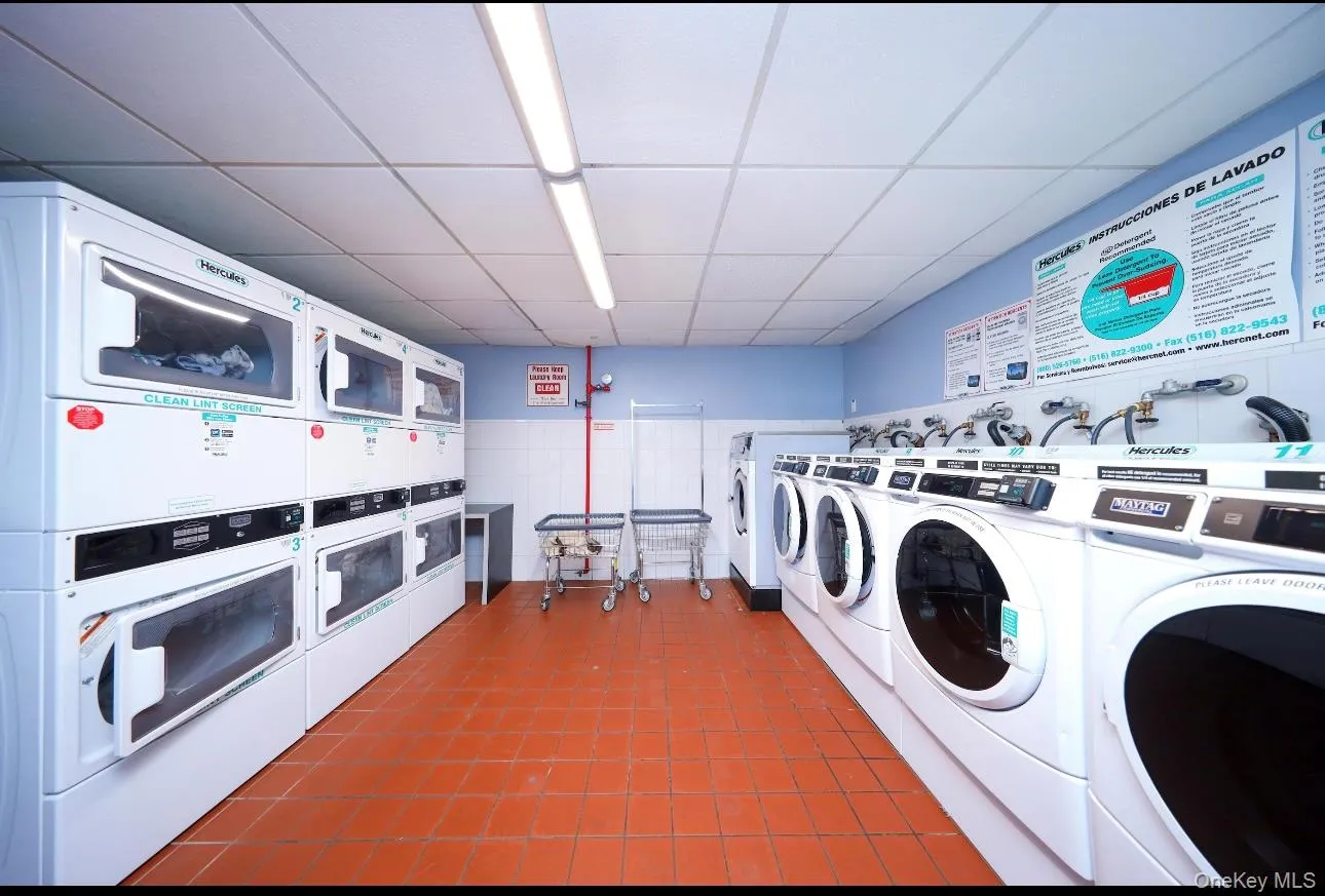 Shared laundry featuring stacked washing machine and dryer, washer and dryer, and dark tile patterned floors Shared laundry featuring stacked washing machine and dryer, washer and dryer, and dark tile patterned floors