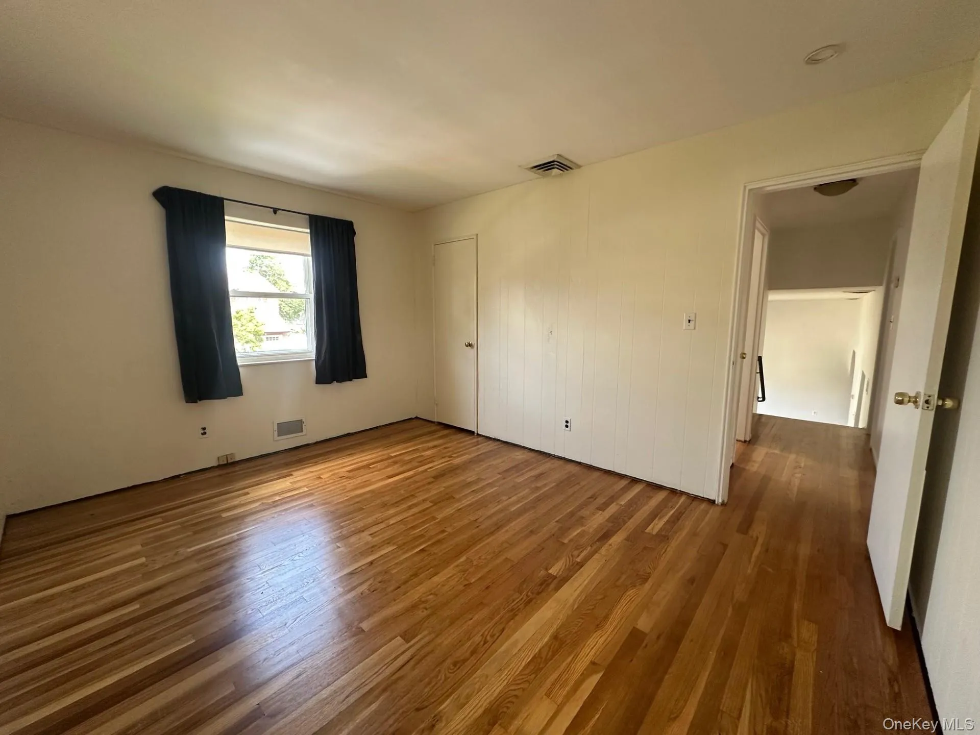 Unfurnished bedroom featuring wood finished floors and a closet Unfurnished bedroom featuring wood finished floors and a closet