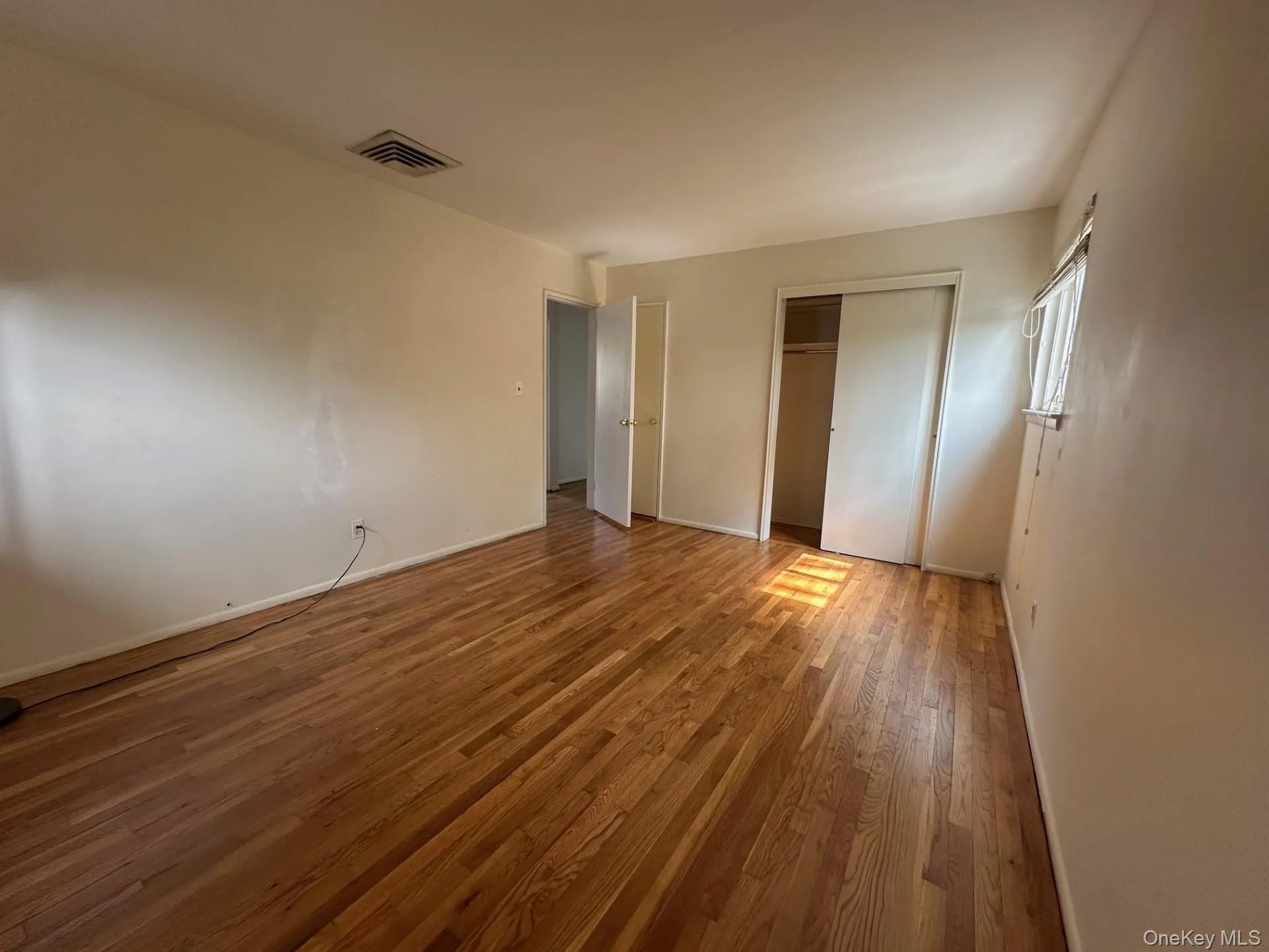 Unfurnished bedroom with a closet and wood finished floors Unfurnished bedroom with a closet and wood finished floors