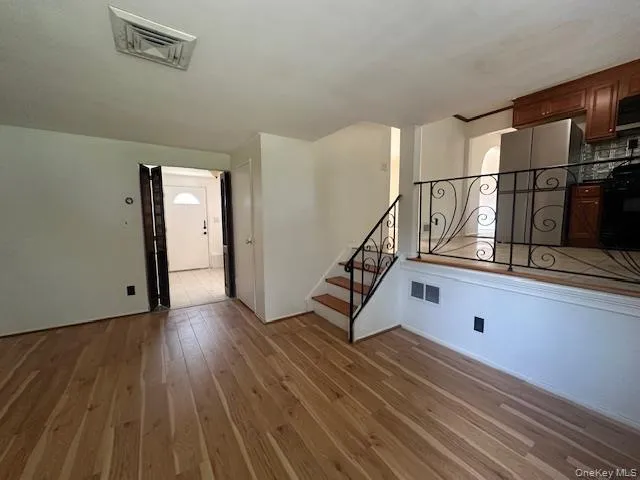 Unfurnished living room featuring light wood-style floors and stairs Unfurnished living room featuring light wood-style floors and stairs