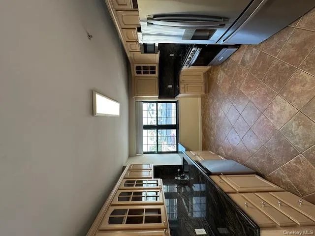 Kitchen with glass insert cabinets, backsplash, fridge, and stainless steel stove Kitchen with glass insert cabinets, backsplash, fridge, and stainless steel stove