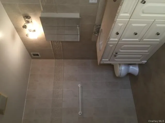 Bathroom with tile walls, double vanity, and tile patterned floors Bathroom with tile walls, double vanity, and tile patterned floors