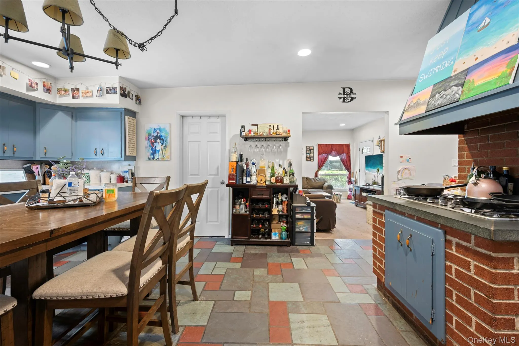 Kitchen with blue cabinetry, extractor fan, recessed lighting, dark countertops, and stone tile flooring Kitchen with blue cabinetry, extractor fan, recessed lighting, dark countertops, and stone tile flooring