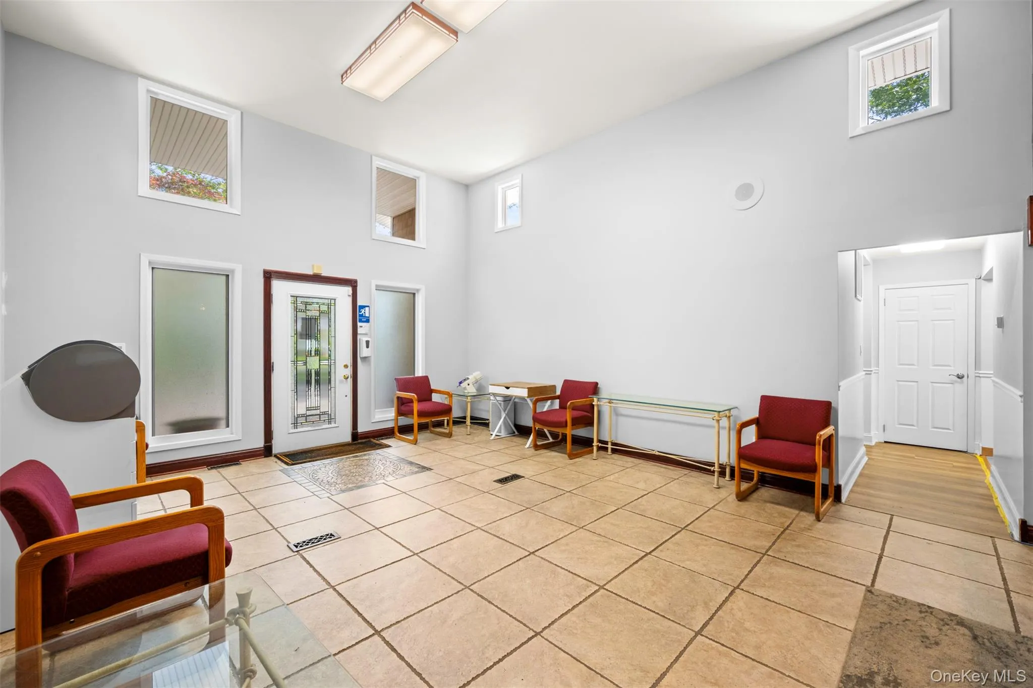 Living area featuring a high ceiling, light tile patterned floors, and plenty of natural light Living area featuring a high ceiling, light tile patterned floors, and plenty of natural light