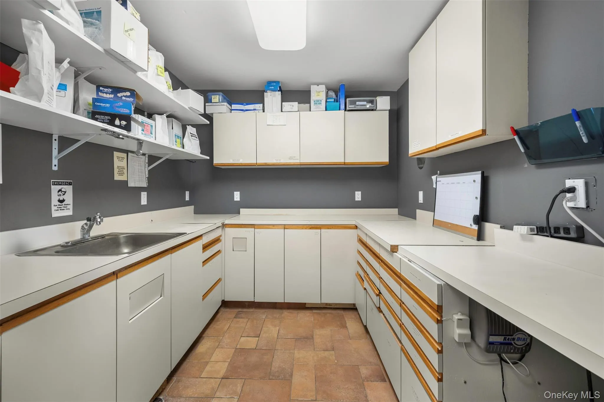 Kitchen with open shelves, white cabinetry, light countertops, and stone finish flooring Kitchen with open shelves, white cabinetry, light countertops, and stone finish flooring