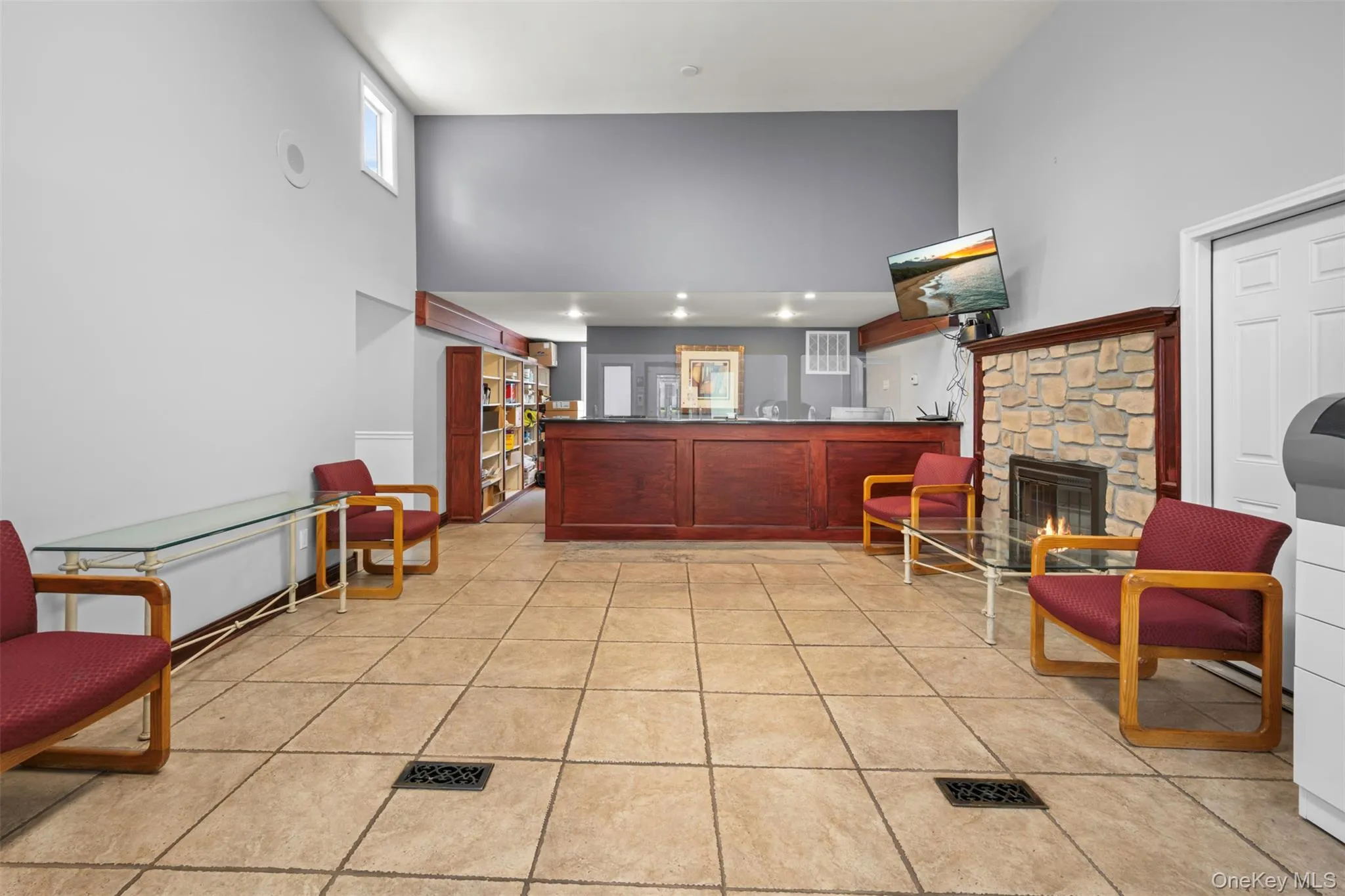 Living room featuring a high ceiling, light tile patterned floors, a stone fireplace, and recessed lighting Living room featuring a high ceiling, light tile patterned floors, a stone fireplace, and recessed lighting