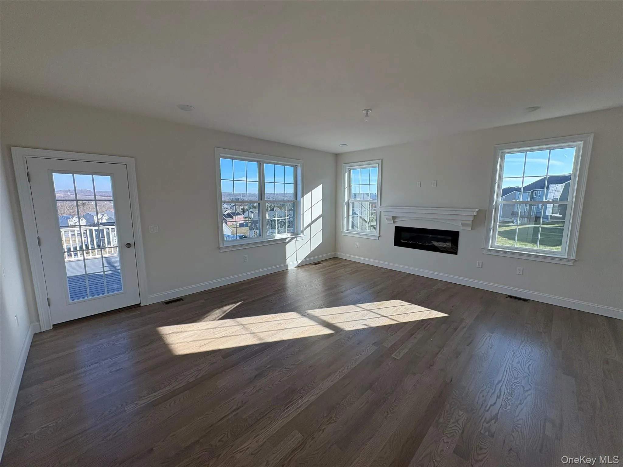 Unfurnished living room with a glass covered fireplace and dark wood-style flooring Unfurnished living room with a glass covered fireplace and dark wood-style flooring