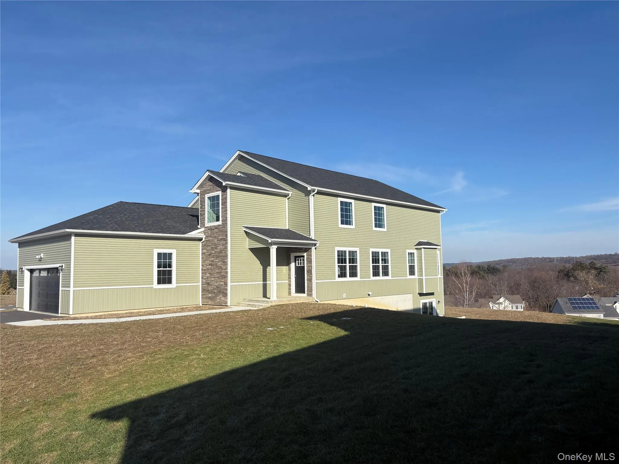 Back of property featuring a lawn, an attached garage, and roof with shingles Back of property featuring a lawn, an attached garage, and roof with shingles