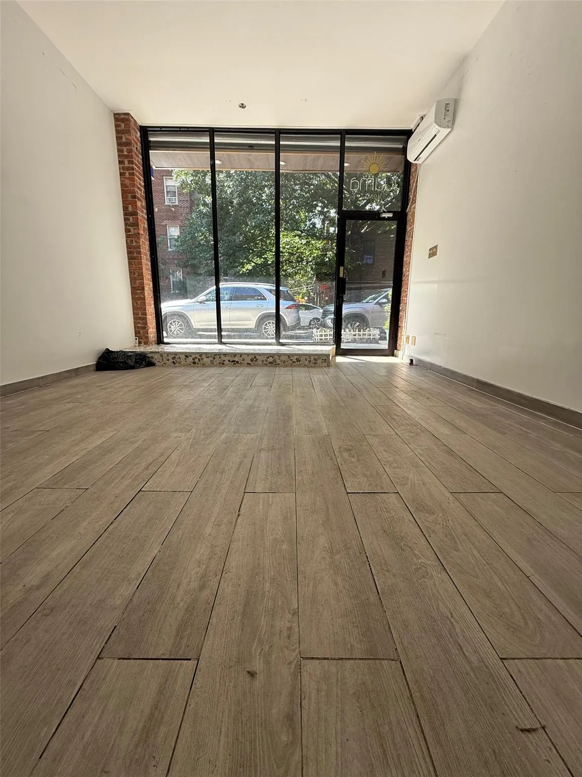 Unfurnished room with expansive windows, wood finished floors, and a wall unit AC Unfurnished room with expansive windows, wood finished floors, and a wall unit AC