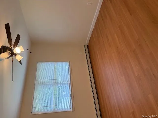 Unfurnished room featuring a baseboard heating unit, light wood-style floors, and ceiling fan Unfurnished room featuring a baseboard heating unit, light wood-style floors, and ceiling fan