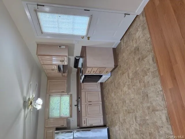 Kitchen with white electric stove, fridge, light brown cabinets, a ceiling fan, and range hood Kitchen with white electric stove, fridge, light brown cabinets, a ceiling fan, and range hood