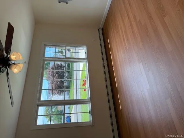 Empty room featuring a baseboard heating unit, a ceiling fan, healthy amount of natural light, and wood finished floors Empty room featuring a baseboard heating unit, a ceiling fan, healthy amount of natural light, and wood finished floors