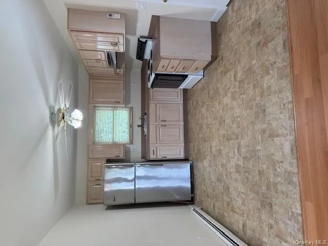 Kitchen with stove, fridge, light brown cabinetry, a baseboard radiator, and a ceiling fan Kitchen with stove, fridge, light brown cabinetry, a baseboard radiator, and a ceiling fan