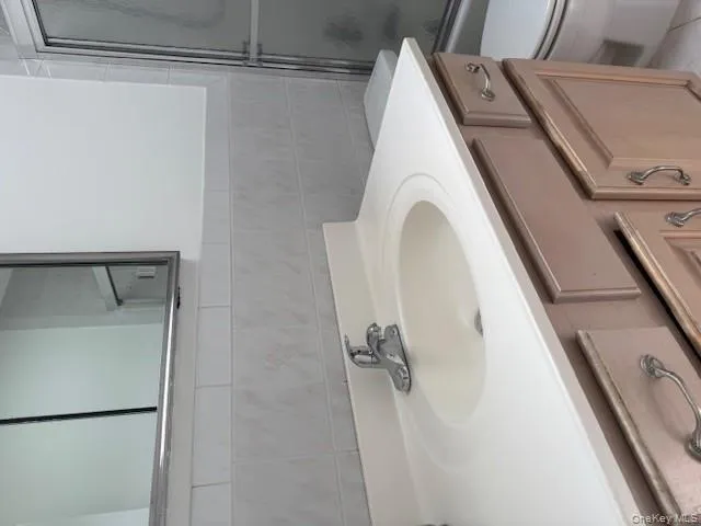 Full bath with vanity, tile walls, and shower / bath combination with glass door Full bath with vanity, tile walls, and shower / bath combination with glass door