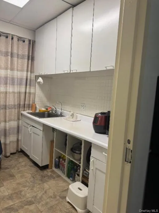 Kitchen featuring backsplash, light countertops, and white cabinets Kitchen featuring backsplash, light countertops, and white cabinets