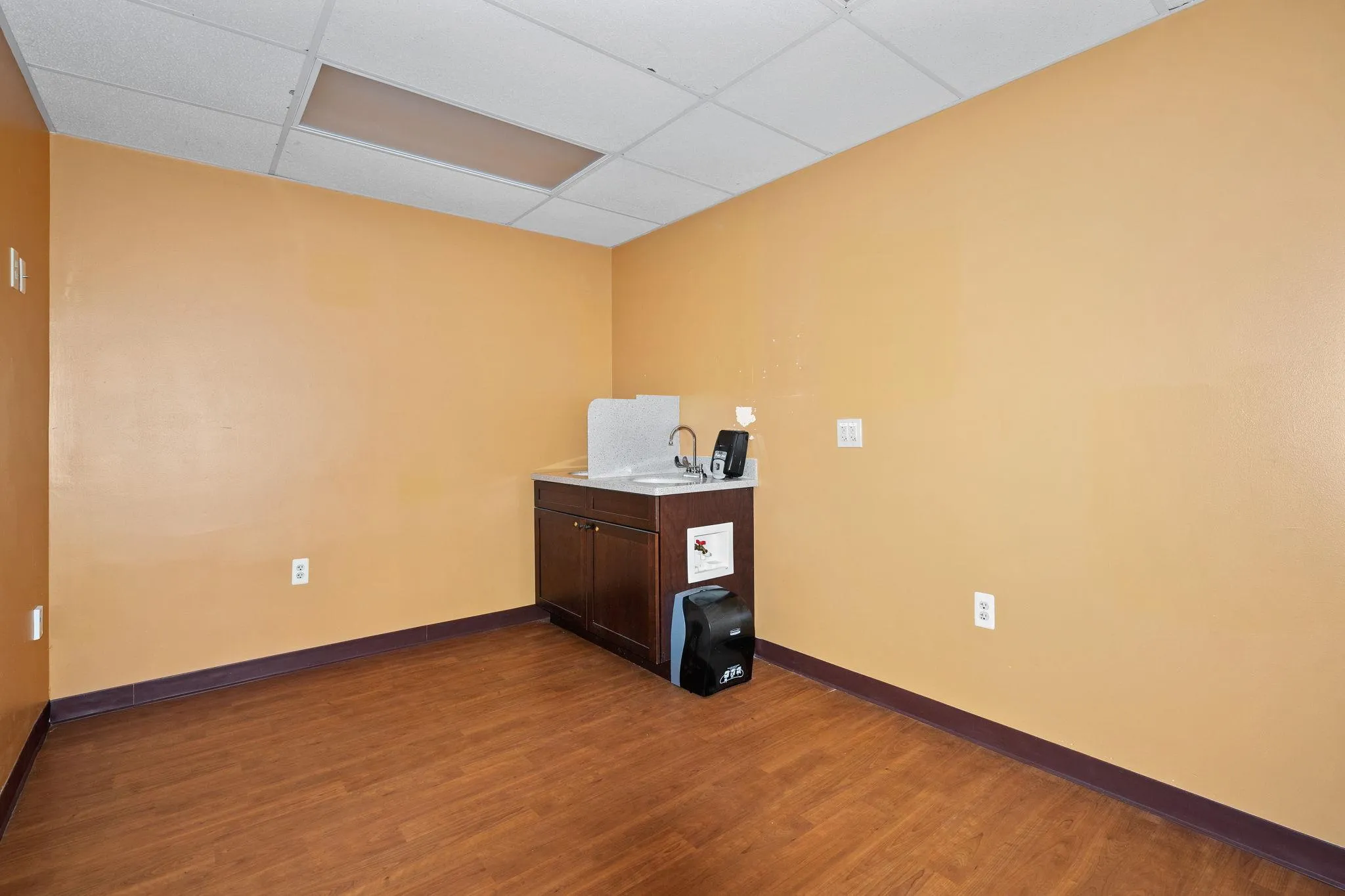Unfurnished room featuring a drop ceiling and dark wood-style floors Unfurnished room featuring a drop ceiling and dark wood-style floors