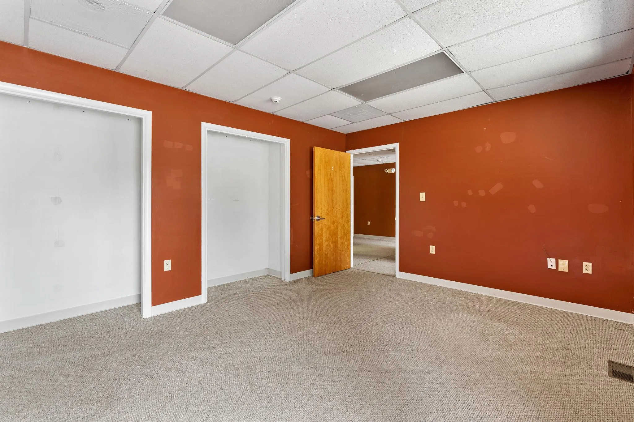 Unfurnished bedroom with a drop ceiling, carpet floors, and a closet Unfurnished bedroom with a drop ceiling, carpet floors, and a closet