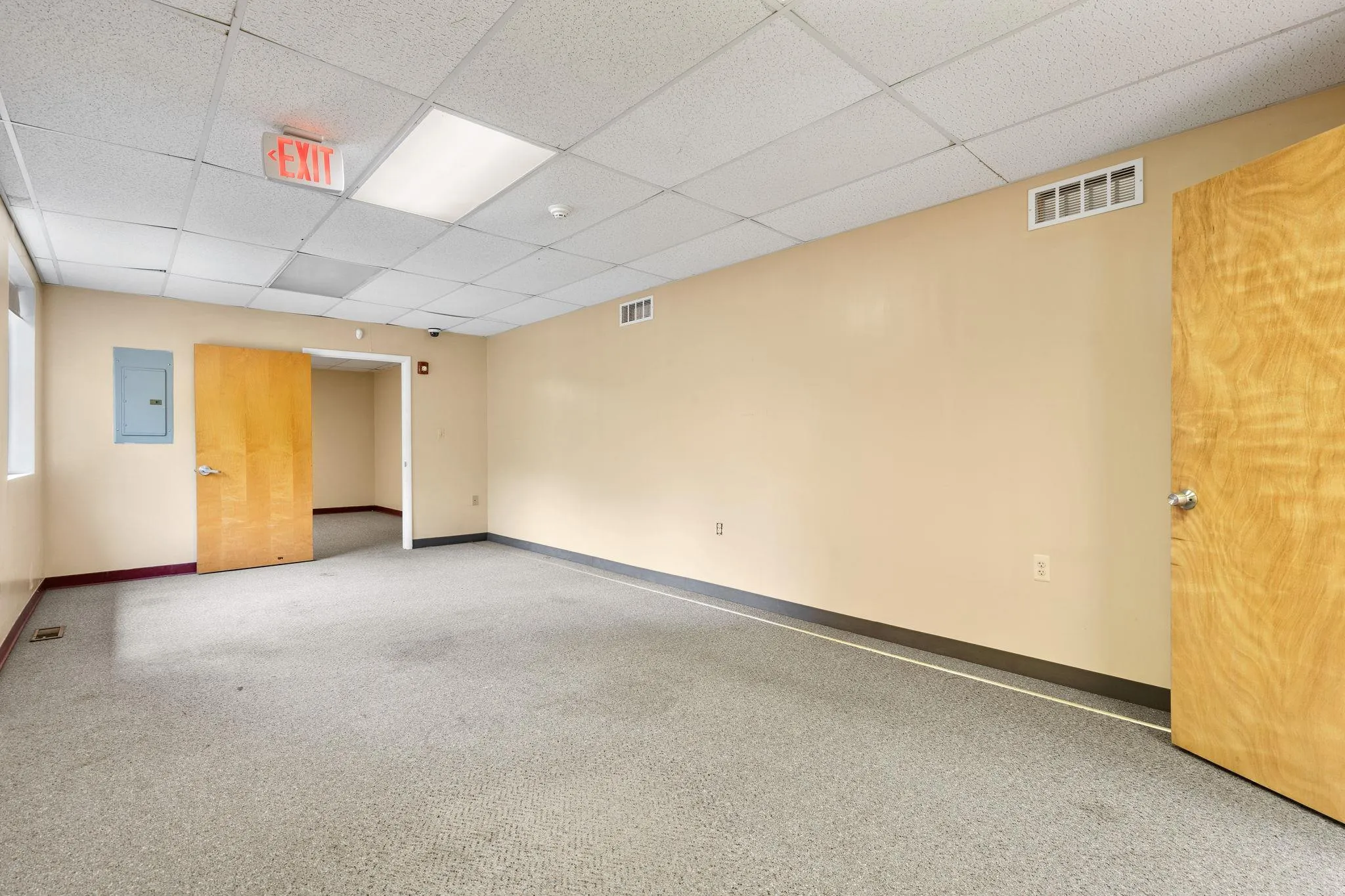 Carpeted empty room featuring a drop ceiling and electric panel Carpeted empty room featuring a drop ceiling and electric panel
