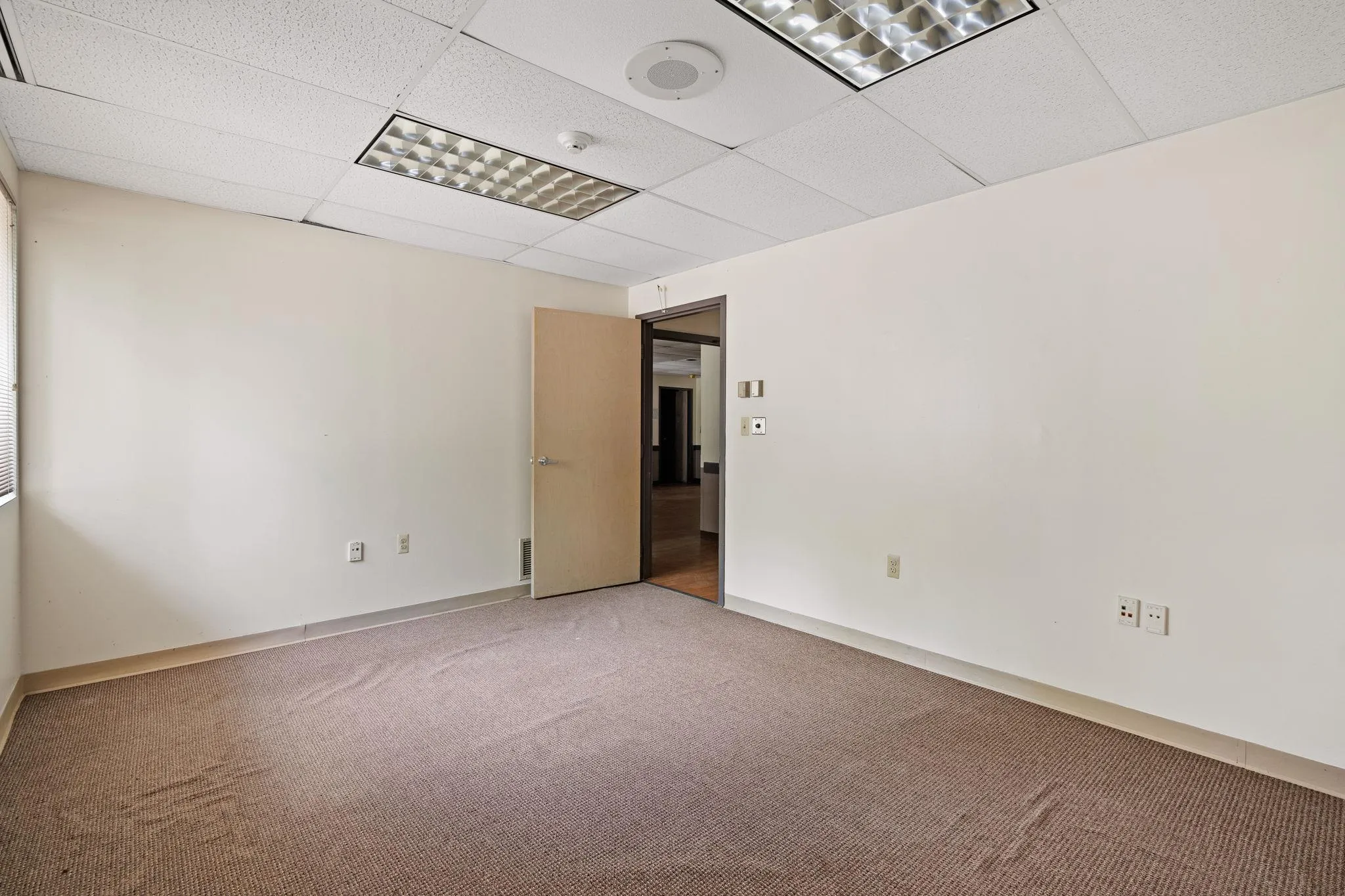 Unfurnished room with light colored carpet and a drop ceiling Unfurnished room with light colored carpet and a drop ceiling