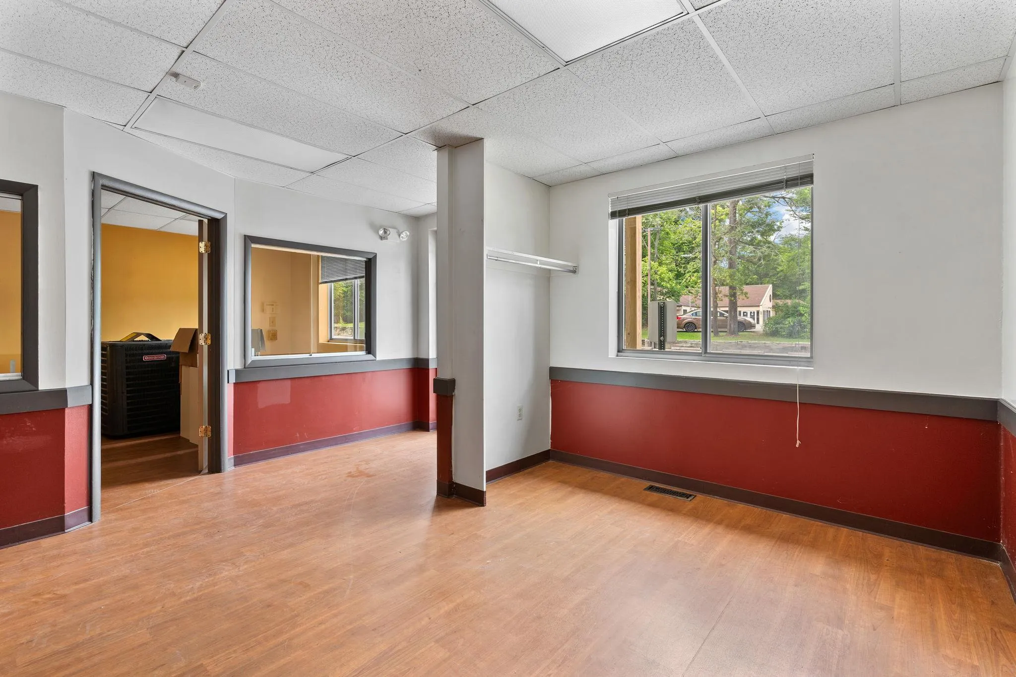 Empty room featuring a paneled ceiling, wood finished floors, and healthy amount of natural light Empty room featuring a paneled ceiling, wood finished floors, and healthy amount of natural light