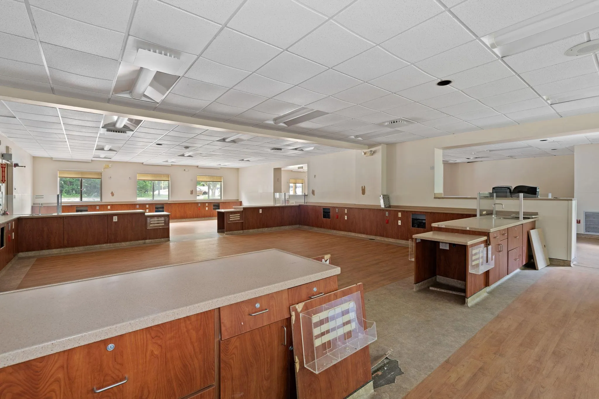 Kitchen featuring a wainscoted wall, light countertops, brown cabinets, open floor plan, and a paneled ceiling Kitchen featuring a wainscoted wall, light countertops, brown cabinets, open floor plan, and a paneled ceiling
