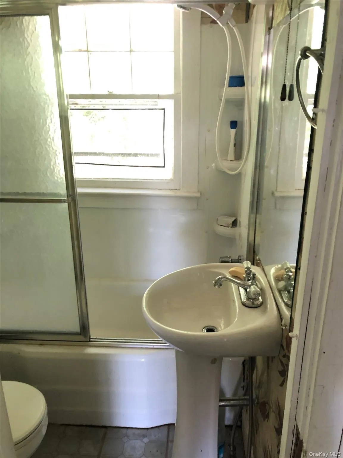 Bathroom featuring bath / shower combo with glass door and tile patterned flooring Bathroom featuring bath / shower combo with glass door and tile patterned flooring