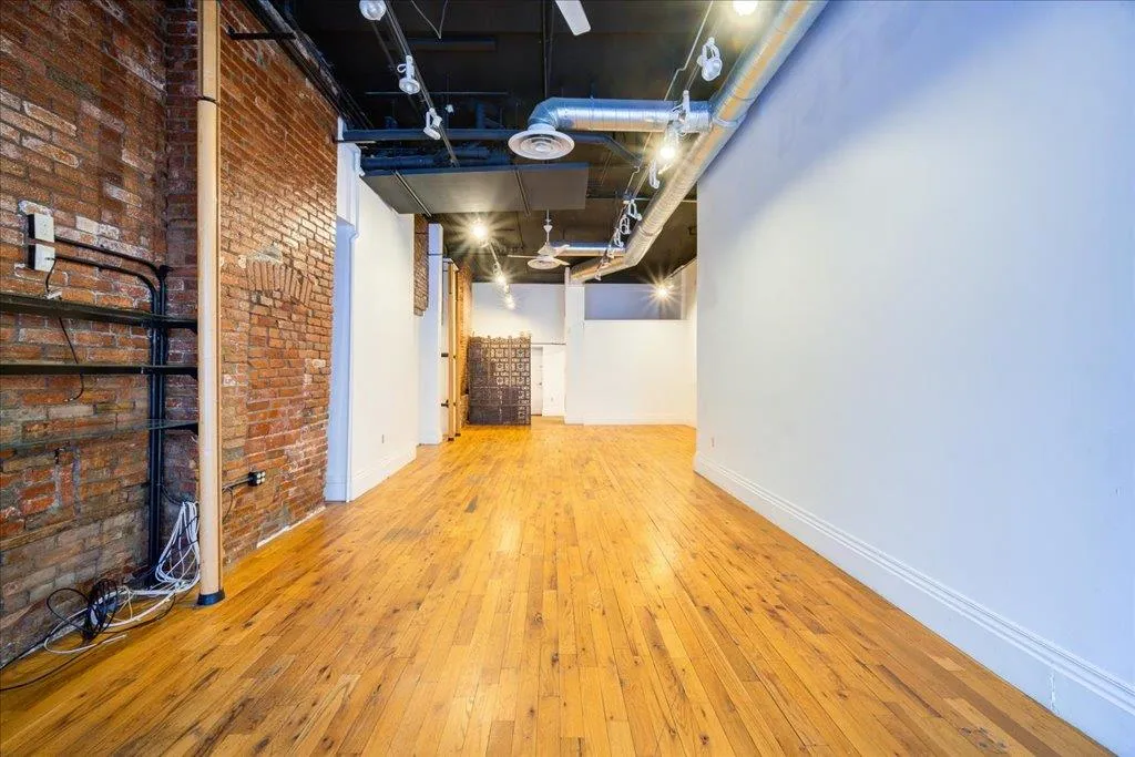 Basement featuring wood-type flooring and brick wall Basement featuring wood-type flooring and brick wall