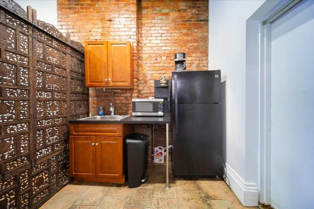 Kitchen with brick wall, black fridge, and sink Kitchen with brick wall, black fridge, and sink