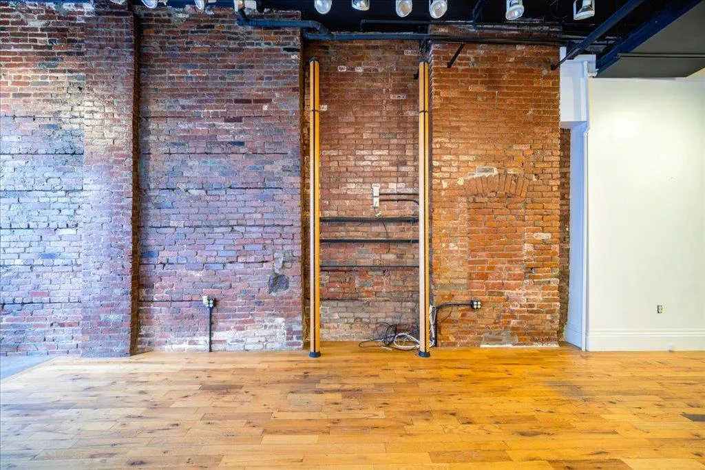 Unfurnished room featuring light hardwood / wood-style floors and brick wall Unfurnished room featuring light hardwood / wood-style floors and brick wall