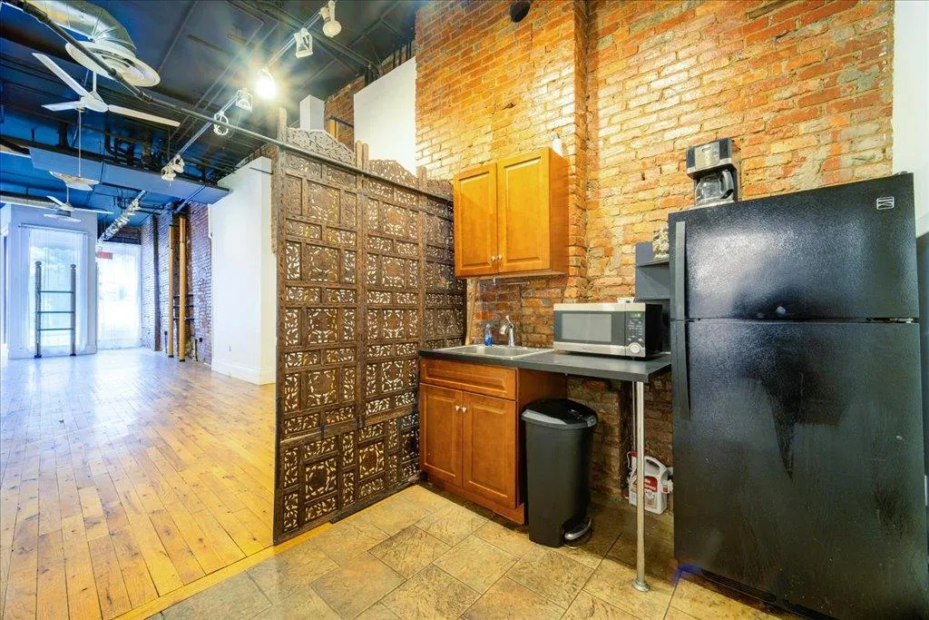 Kitchen featuring black refrigerator, brick wall, and sink Kitchen featuring black refrigerator, brick wall, and sink