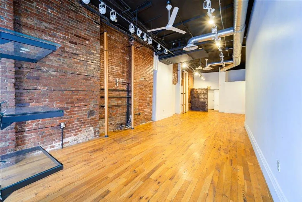 Unfurnished living room with brick wall and hardwood / wood-style floors Unfurnished living room with brick wall and hardwood / wood-style floors