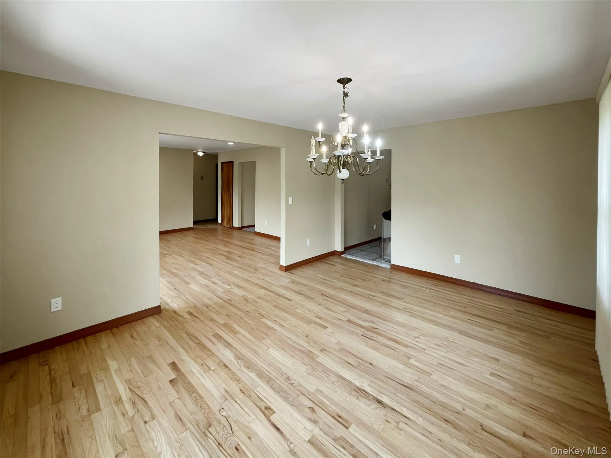 Unfurnished room with a chandelier and light wood-style floors Unfurnished room with a chandelier and light wood-style floors