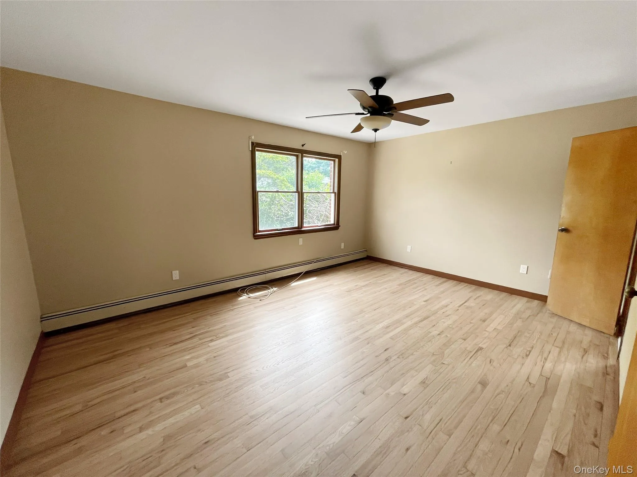 Unfurnished room featuring a baseboard radiator, light wood-style flooring, and ceiling fan Unfurnished room featuring a baseboard radiator, light wood-style flooring, and ceiling fan