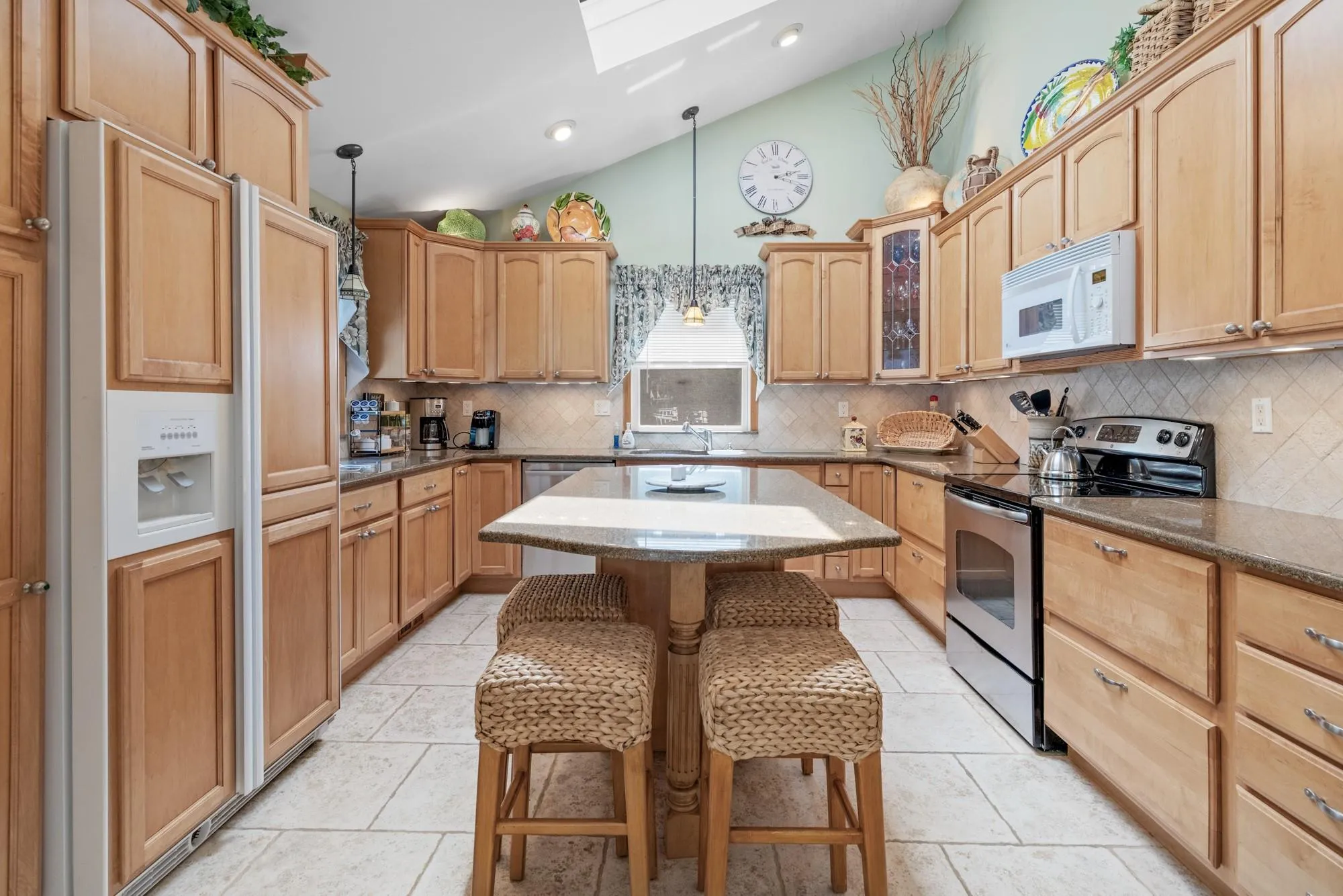 Kitchen featuring a skylight, stainless steel appliances, lofted ceiling, backsplash, and a kitchen island Kitchen featuring a skylight, stainless steel appliances, lofted ceiling, backsplash, and a kitchen island