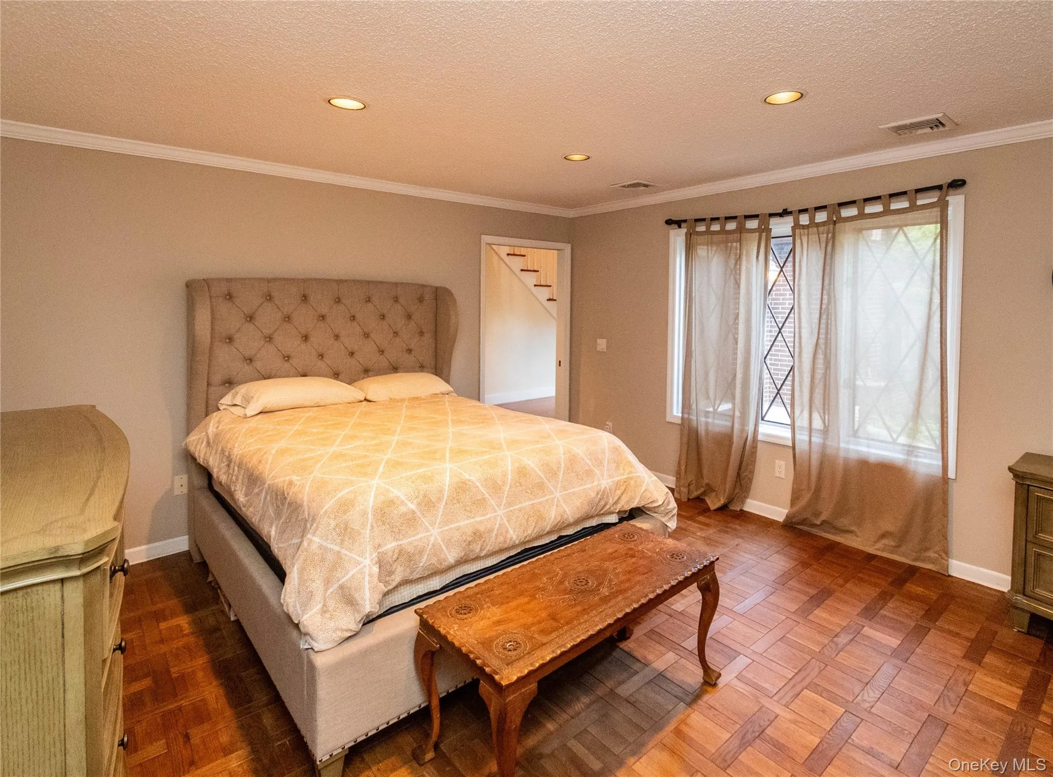 Bedroom featuring ornamental molding, recessed lighting, and a textured ceiling Bedroom featuring ornamental molding, recessed lighting, and a textured ceiling