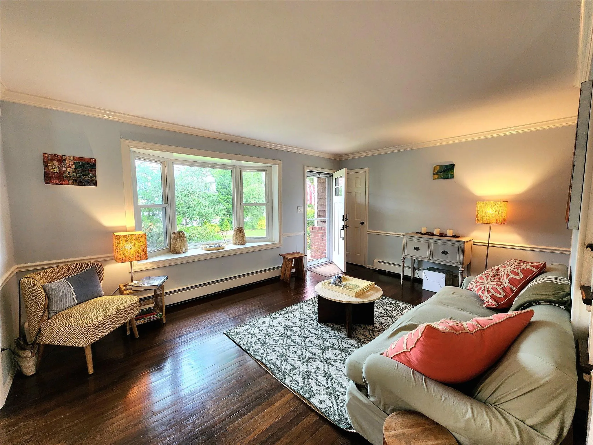 Living room featuring ornamental molding, wood finished floors, and a baseboard heating unit Living room featuring ornamental molding, wood finished floors, and a baseboard heating unit