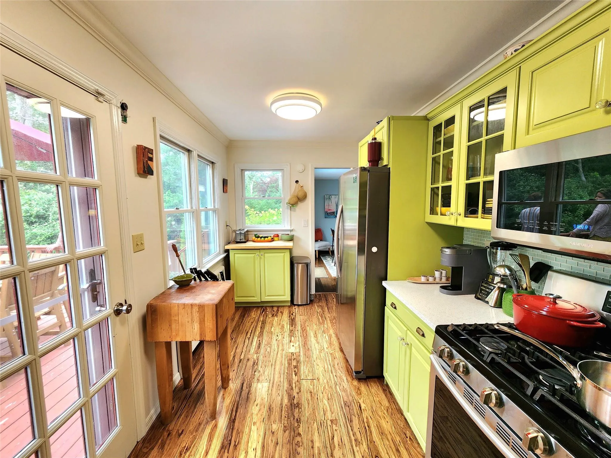 Kitchen featuring green cabinetry, appliances with stainless steel finishes, light wood-type flooring, light countertops, and ornamental molding Kitchen featuring green cabinetry, appliances with stainless steel finishes, light wood-type flooring, light countertops, and ornamental molding